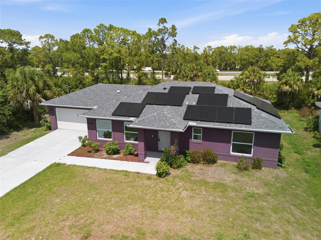 An aerial view of a purple single-story house with solar panels on the roof — 7530 FRANZINO AVENUE, NORTH PORT, FL