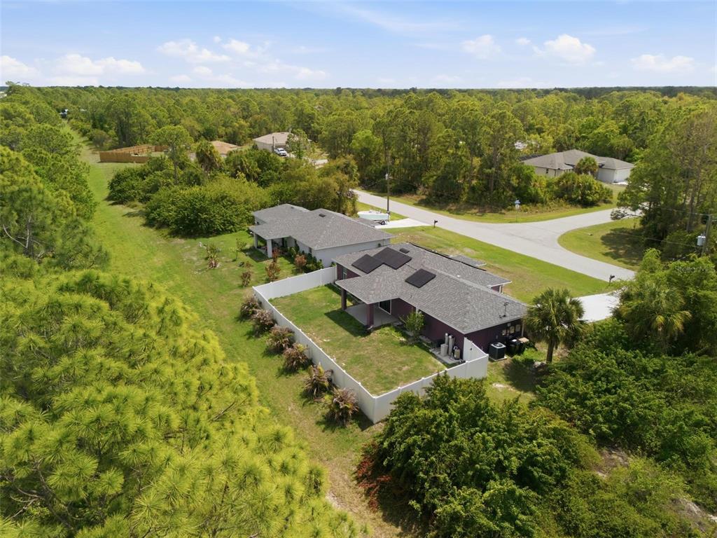 An aerial view shows a house with a fenced backyard surrounded by dense green trees — 7530 FRANZINO AVENUE, NORTH PORT, FL