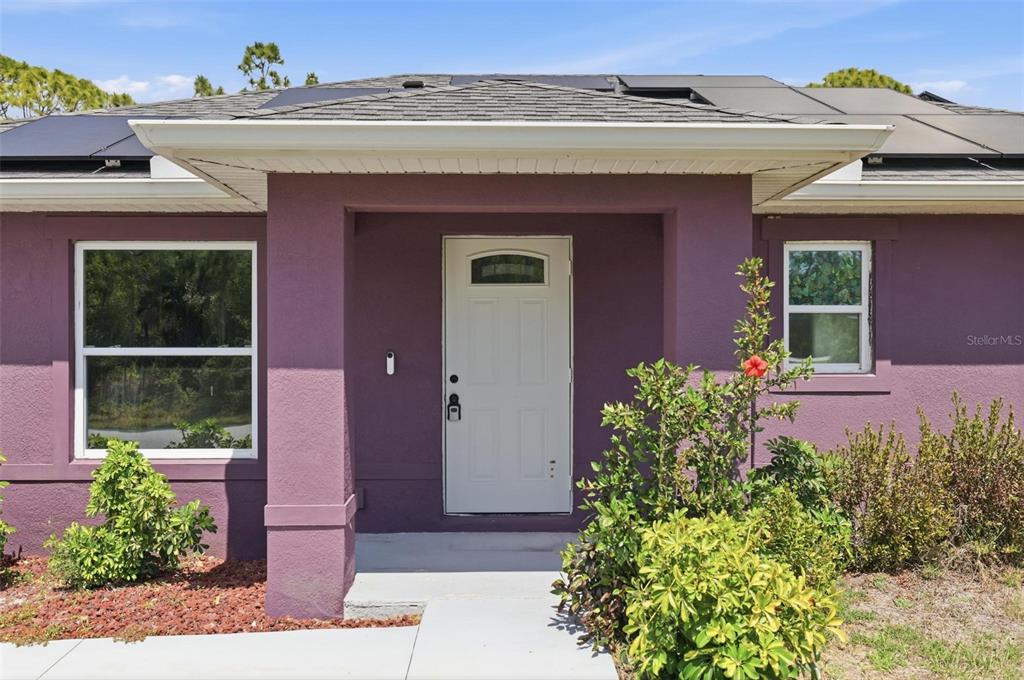 The exterior of a purple house features a white front door and solar panels — 7530 FRANZINO AVENUE, NORTH PORT, FL