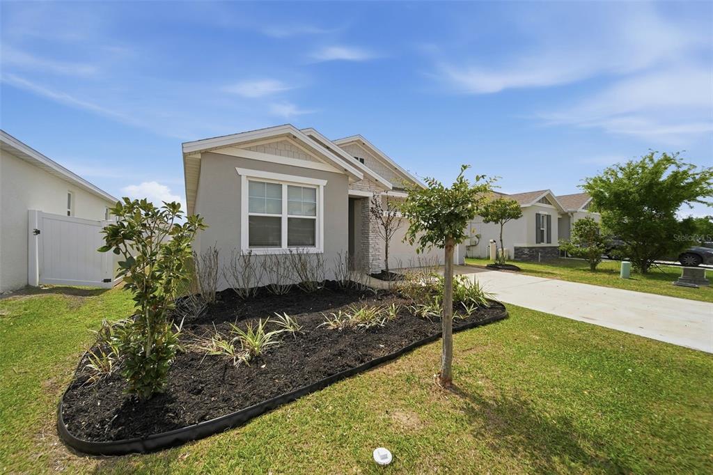 A single-story house with a gray exterior, a front garden bed, and a concrete driveway — 1120 MATTIE POINTE BOULEVARD, AUBURNDALE, FL