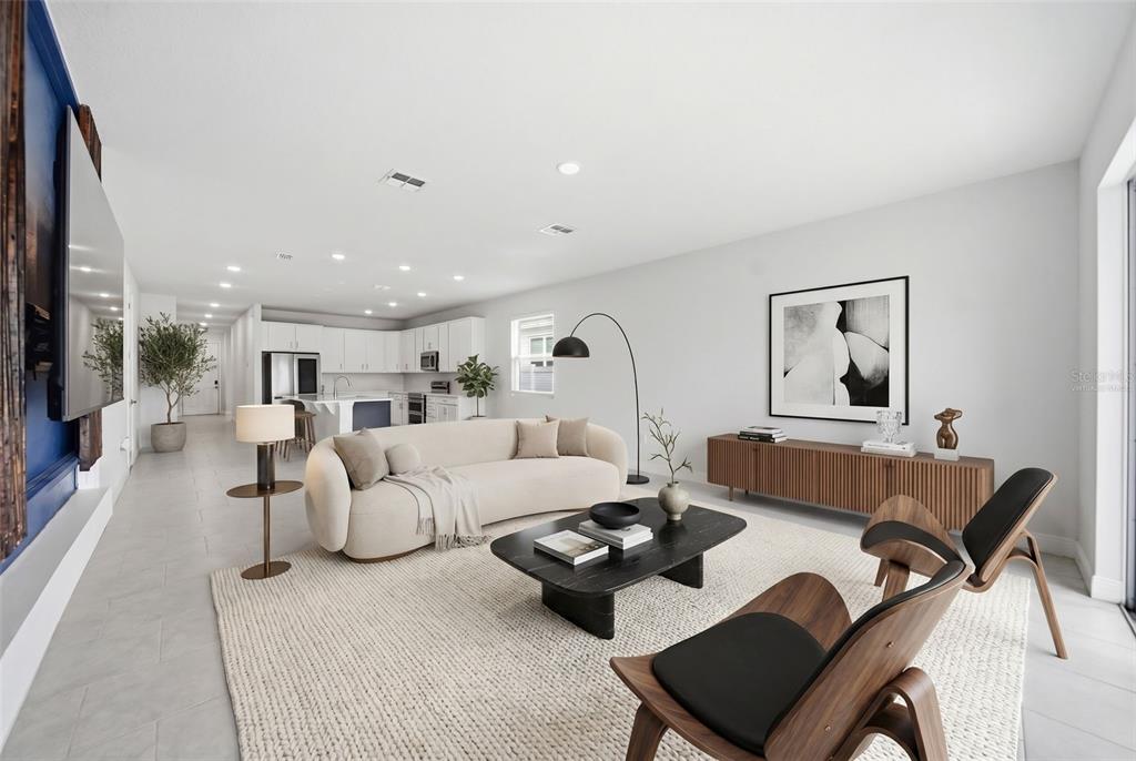 A modern open-concept living room features a curved sofa, black coffee table, and wood console — 1120 MATTIE POINTE BOULEVARD, AUBURNDALE, FL
