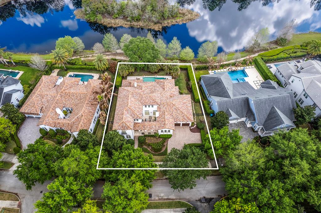 An aerial view shows a house with a tiled roof, pool, and landscaping near water — 1735 FOSS AVENUE, ORLANDO, FL