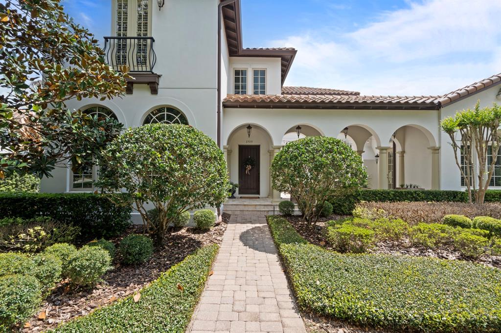 A paved walkway leads to the arched entryway of a two-story stucco home — 1735 FOSS AVENUE, ORLANDO, FL