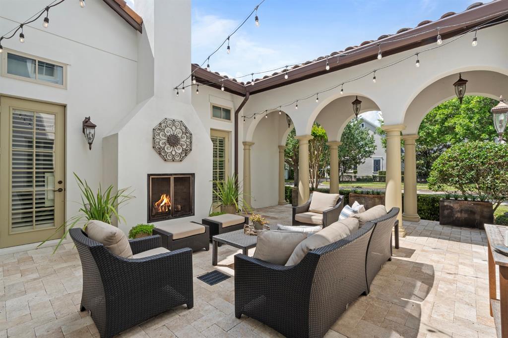 A covered patio features a stone fireplace, wicker furniture, and string lights on a paved floor — 1735 FOSS AVENUE, ORLANDO, FL