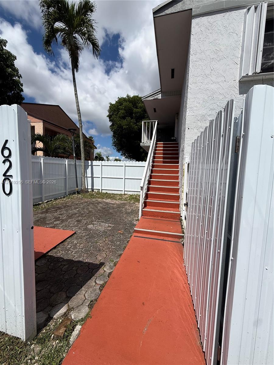 An exterior view shows a red staircase leading to an upper-level entrance beside a fence — 8480 SW 156th Pl # 620, Miami FL 33193, MIAMI, FL