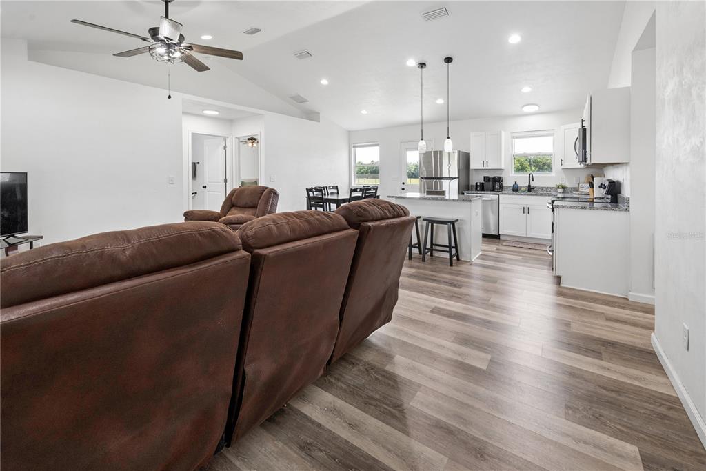 An open-concept living room and kitchen with wood-look flooring, white cabinets, and a ceiling fan — 21411 NW 209TH TERRACE, HIGH SPRINGS, FL