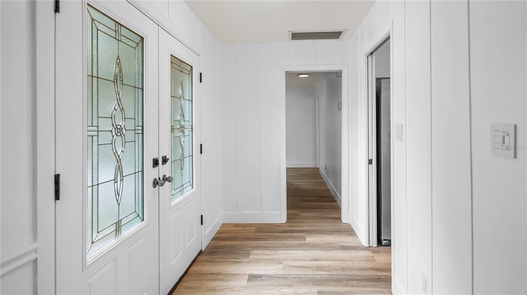 A white entryway features a double front door with glass panels and wood-look flooring — 901 CUTLER ROAD, LONGWOOD, FL