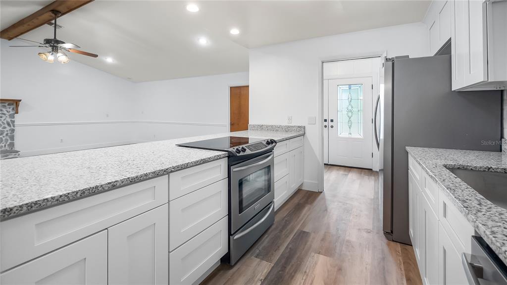 A kitchen features white cabinets, granite countertops, stainless steel appliances, and wood-look flooring — 901 CUTLER ROAD, LONGWOOD, FL