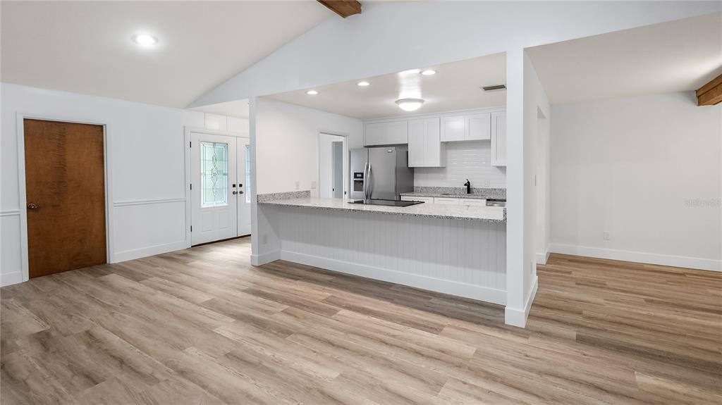 A kitchen with white cabinets and a granite breakfast bar overlooks a living area — 901 CUTLER ROAD, LONGWOOD, FL