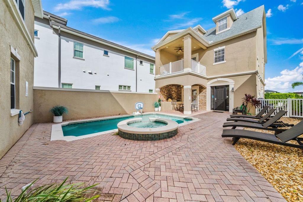 A backyard patio features a swimming pool, a hot tub, and lounge chairs — 1525 COROLLA COURT, REUNION, FL