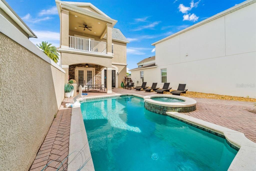 A backyard features a swimming pool, a raised hot tub, and a two-story house — 1525 COROLLA COURT, REUNION, FL