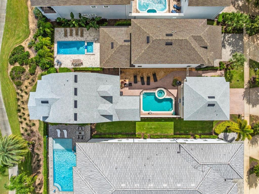 Aerial view of three adjacent houses with private swimming pools and landscaped backyards — 1525 COROLLA COURT, REUNION, FL