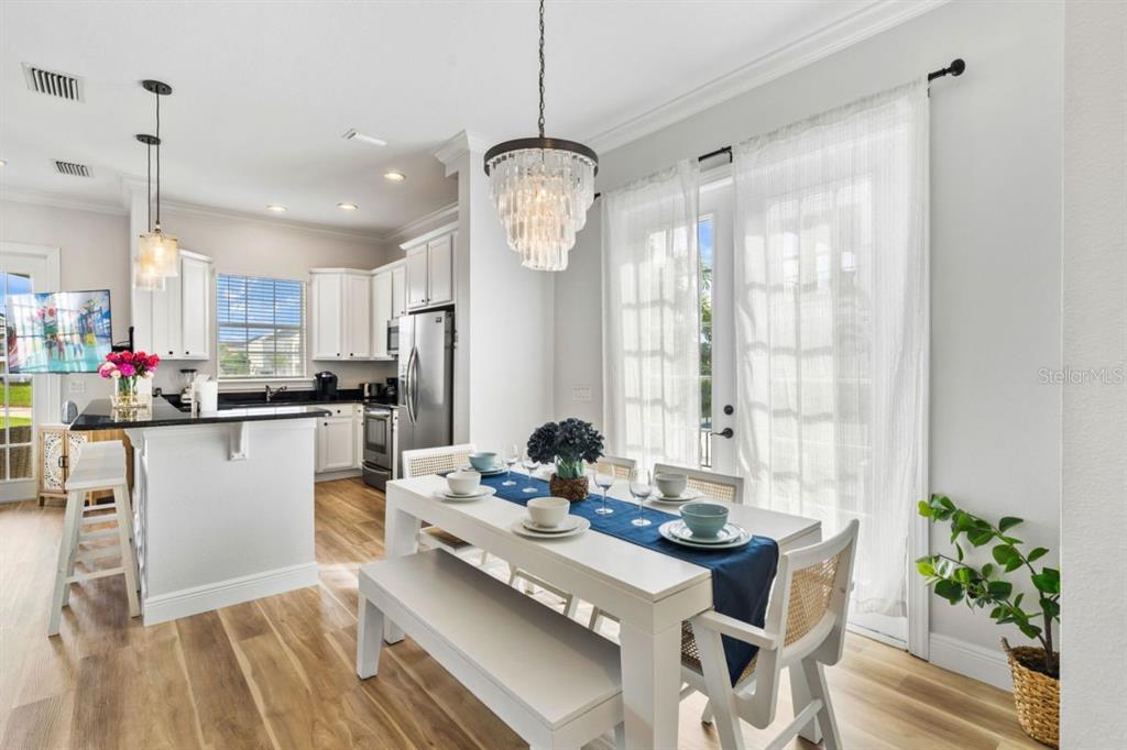 A dining area with a white table and bench sits adjacent to a white kitchen — 1525 COROLLA COURT, REUNION, FL