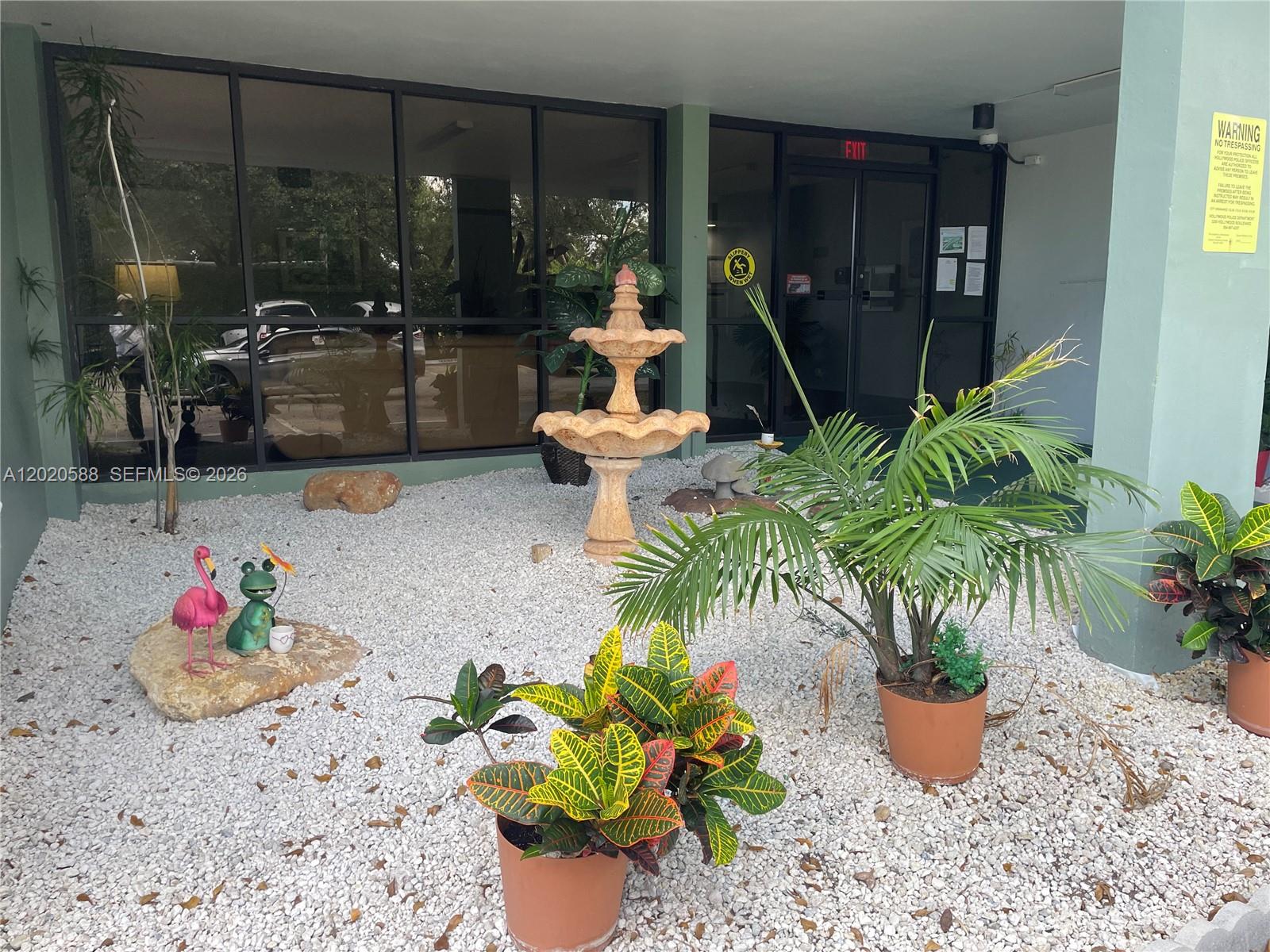 A small courtyard features a stone fountain, potted plants, and decorative figurines on white gravel — 2731 Taft St # 311, Hollywood FL 33020, HOLLYWOOD, FL