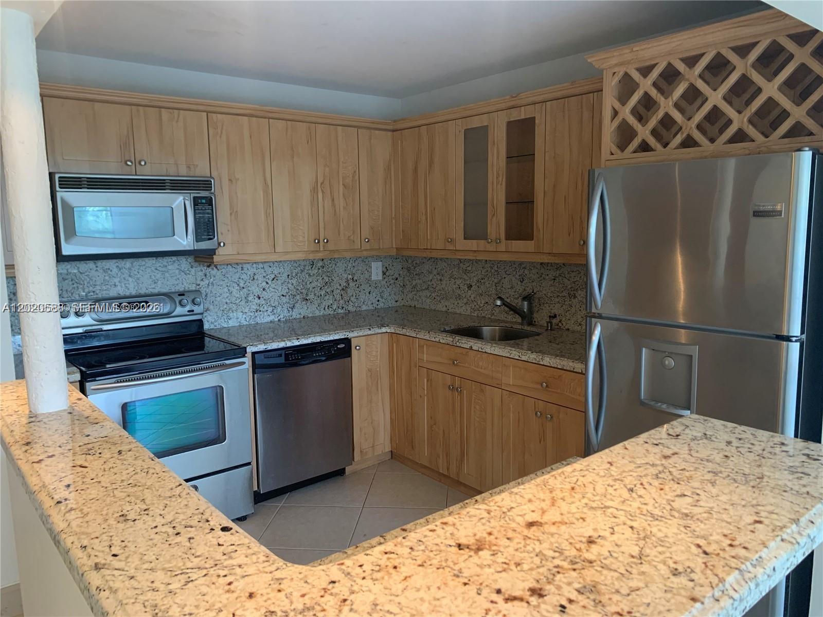 A kitchen features light wood cabinets, stainless steel appliances, and speckled granite countertops — 2731 Taft St # 311, Hollywood FL 33020, HOLLYWOOD, FL