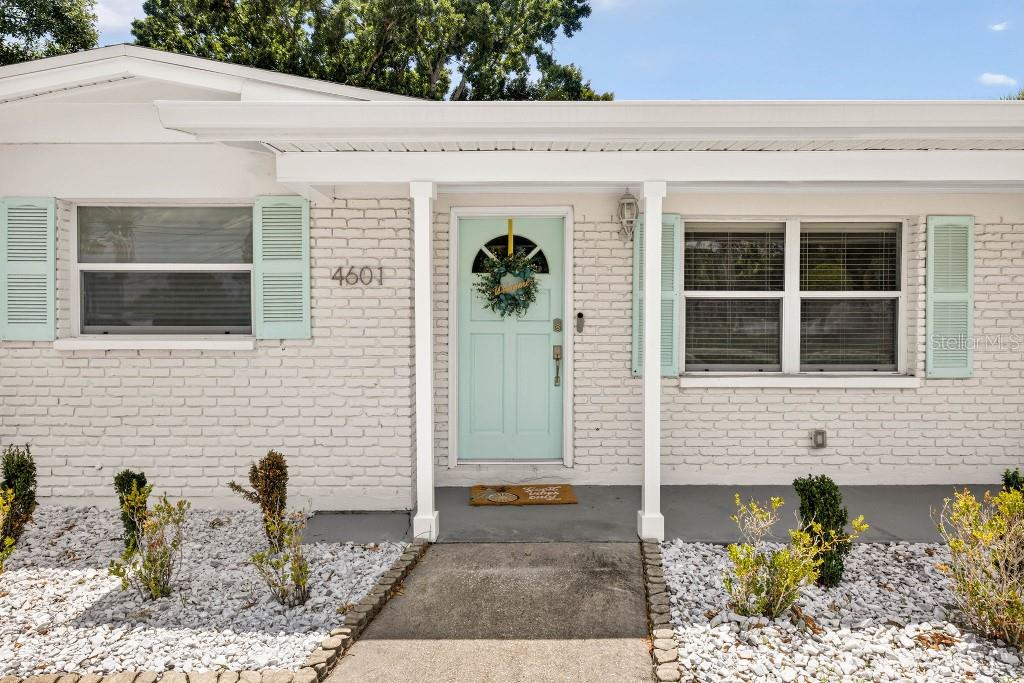A white brick house exterior features a light blue front door and matching window shutters — 4601 S CLARK AVENUE, TAMPA, FL