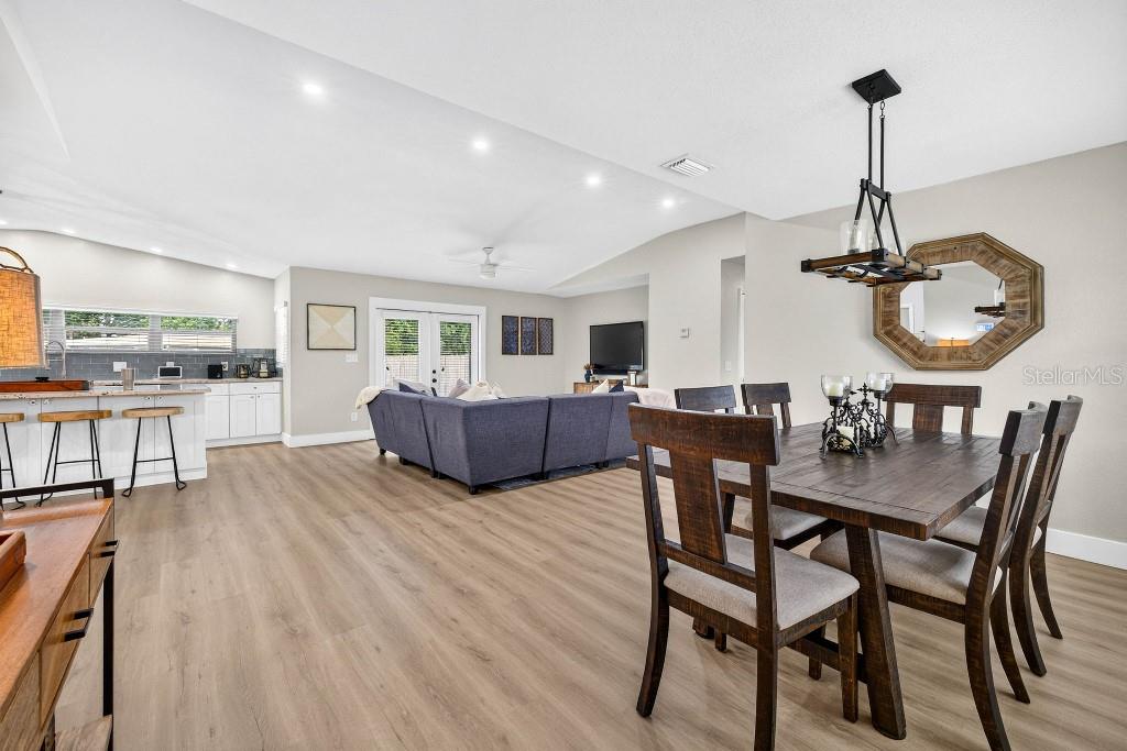An open-concept living and dining area features light wood flooring and a vaulted ceiling — 4601 S CLARK AVENUE, TAMPA, FL