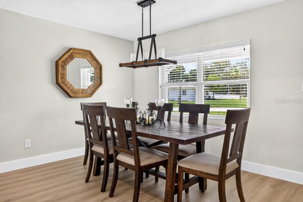 A dining room features a wooden table with six chairs, a chandelier, and a wall mirror — 4601 S CLARK AVENUE, TAMPA, FL
