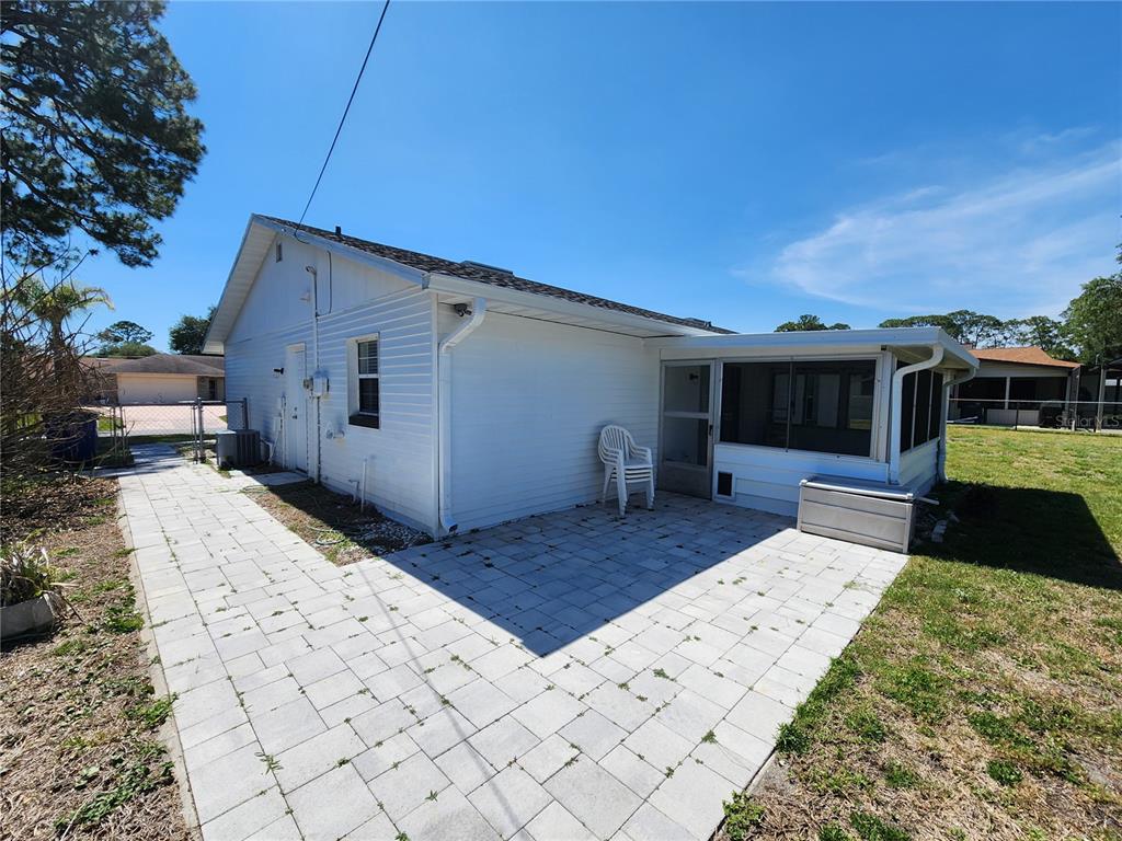 A white house exterior features a paved patio and a screened-in porch — 2827 ROYAL PALM DRIVE, EDGEWATER, FL