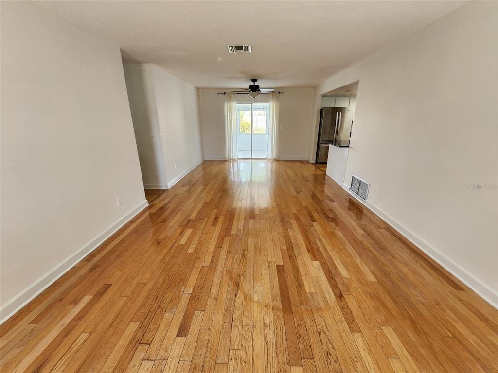 An empty living room features hardwood floors, a ceiling fan, and a sliding glass door — 2827 ROYAL PALM DRIVE, EDGEWATER, FL