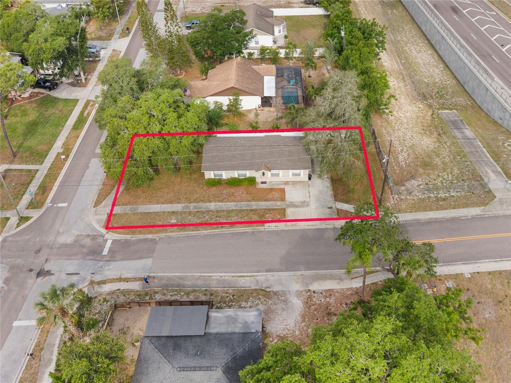 An aerial view shows a single-story house with a driveway, surrounded by trees and grass — 1221 E COURT STREET, TARPON SPRINGS, FL