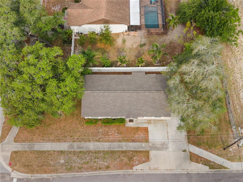 An aerial view shows a single-story house with a shingled roof, driveway, and surrounding trees — 1221 E COURT STREET, TARPON SPRINGS, FL