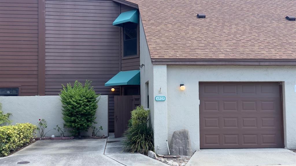 A two-story townhouse exterior features brown horizontal siding, stucco walls, and a single-car garage — 4525 PARK LAKE TERRACE S UNIT 4525, BRADENTON, FL