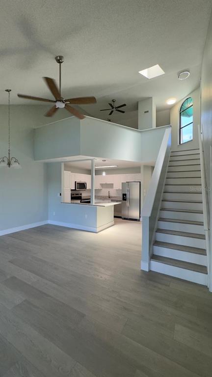 An open-concept living area features light wood flooring, a kitchen, and a staircase — 4525 PARK LAKE TERRACE S UNIT 4525, BRADENTON, FL