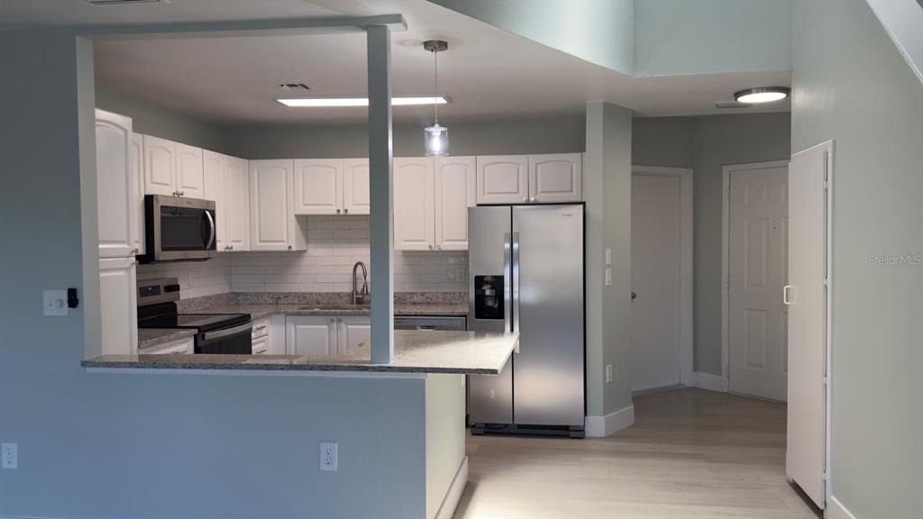 A kitchen with white cabinets, granite countertops, stainless steel appliances, and a breakfast bar — 4525 PARK LAKE TERRACE S UNIT 4525, BRADENTON, FL