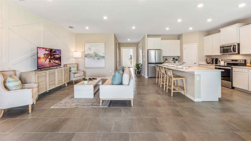 An open-concept living room and kitchen featuring tile flooring, white cabinetry, and recessed lighting — 3507 HARVEST GARDENS LOOP, PLANT CITY, FL