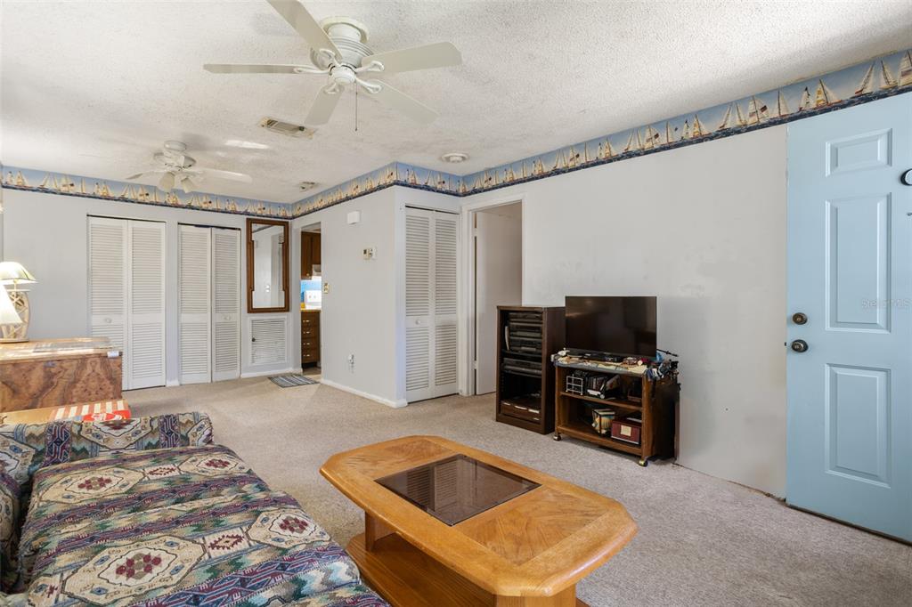 A living room features a patterned sofa, a wooden coffee table, and a light blue door — 3216 39TH STREET UNIT C, ST PETERSBURG, FL