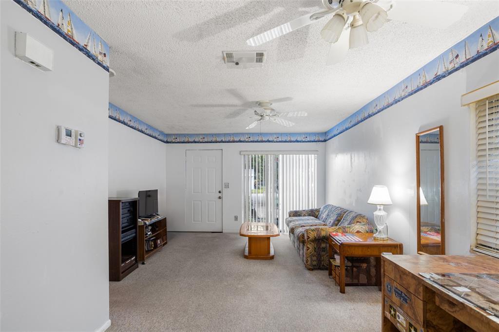 A living room features carpeted floors, a ceiling fan, a patterned sofa, and nautical wallpaper borders — 3216 39TH STREET UNIT C, ST PETERSBURG, FL