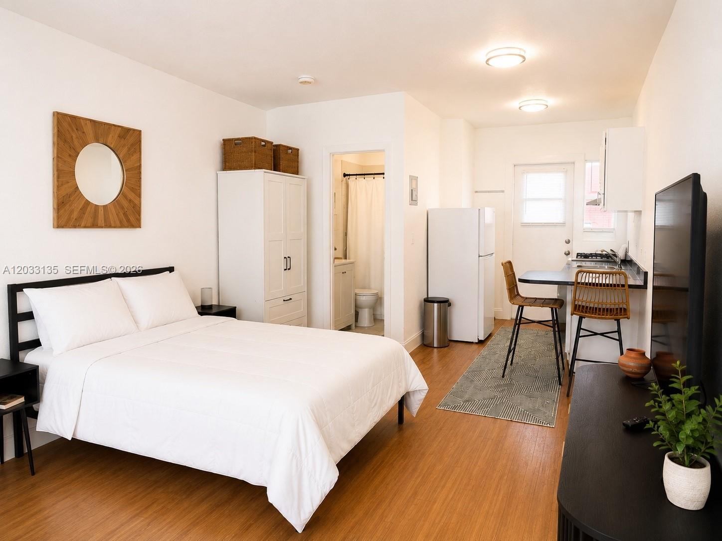A studio apartment features a bed, a small kitchen area, and a bathroom entrance — 300 74th St # 5, Miami Beach FL 33141, MIAMI BEACH, FL