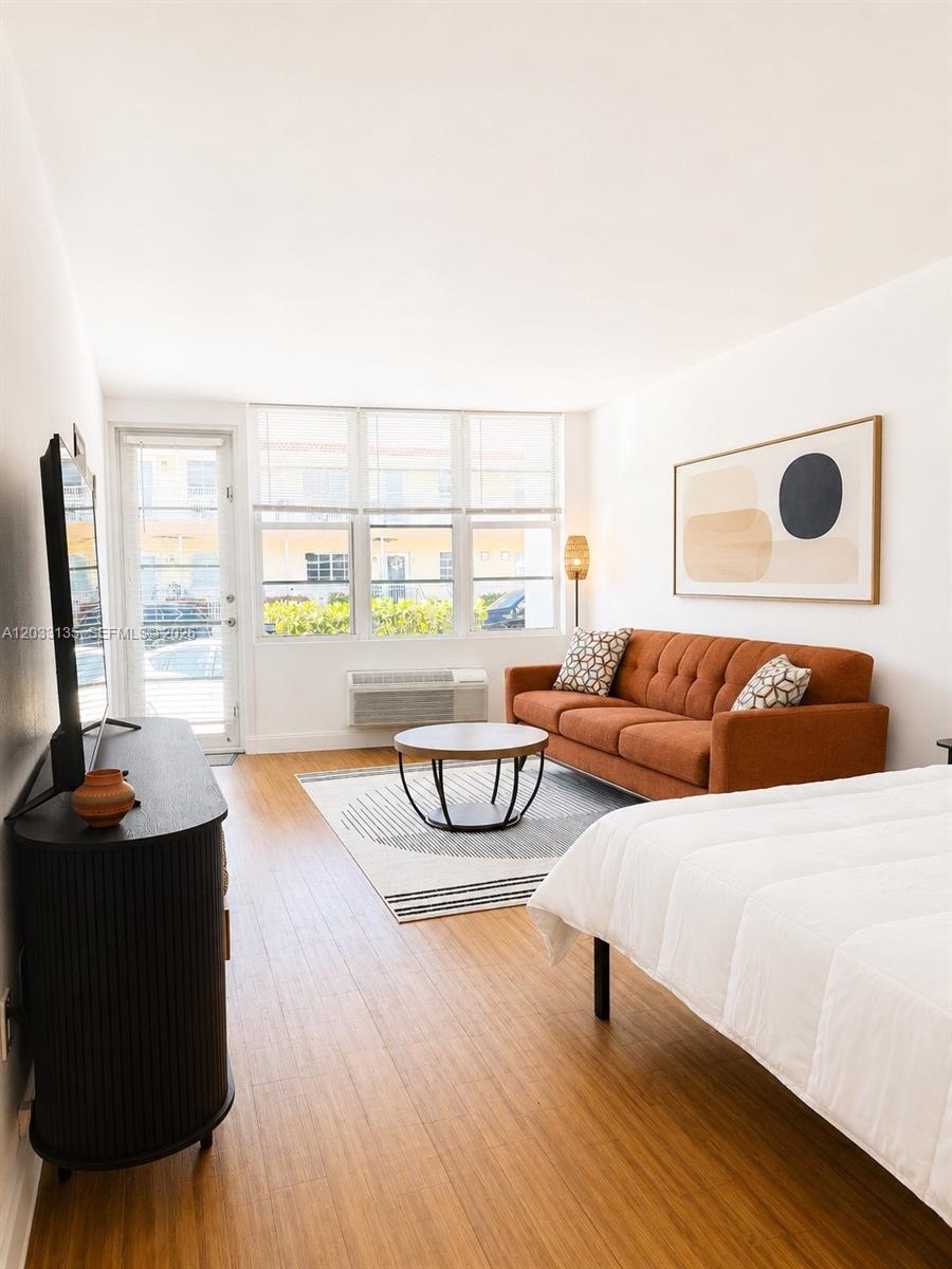 A studio apartment features a bed, an orange sofa, a coffee table, and a balcony door — 300 74th St # 5, Miami Beach FL 33141, MIAMI BEACH, FL