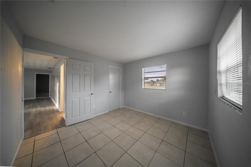 An empty room features light-colored tile flooring, gray walls, two doors, and a window — 1706 N 29TH STREET, FORT PIERCE, FL