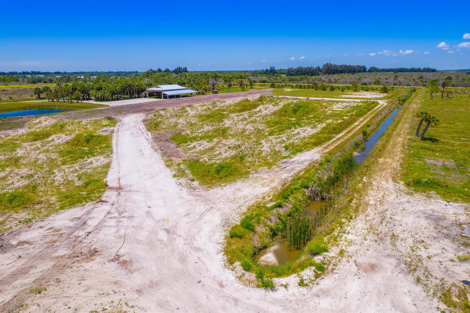 An aerial view of a large, undeveloped dirt lot with a small pond and pavilion — 0 Orange Avenue, Fort Pierce FL 34945, FORT PIERCE, FL