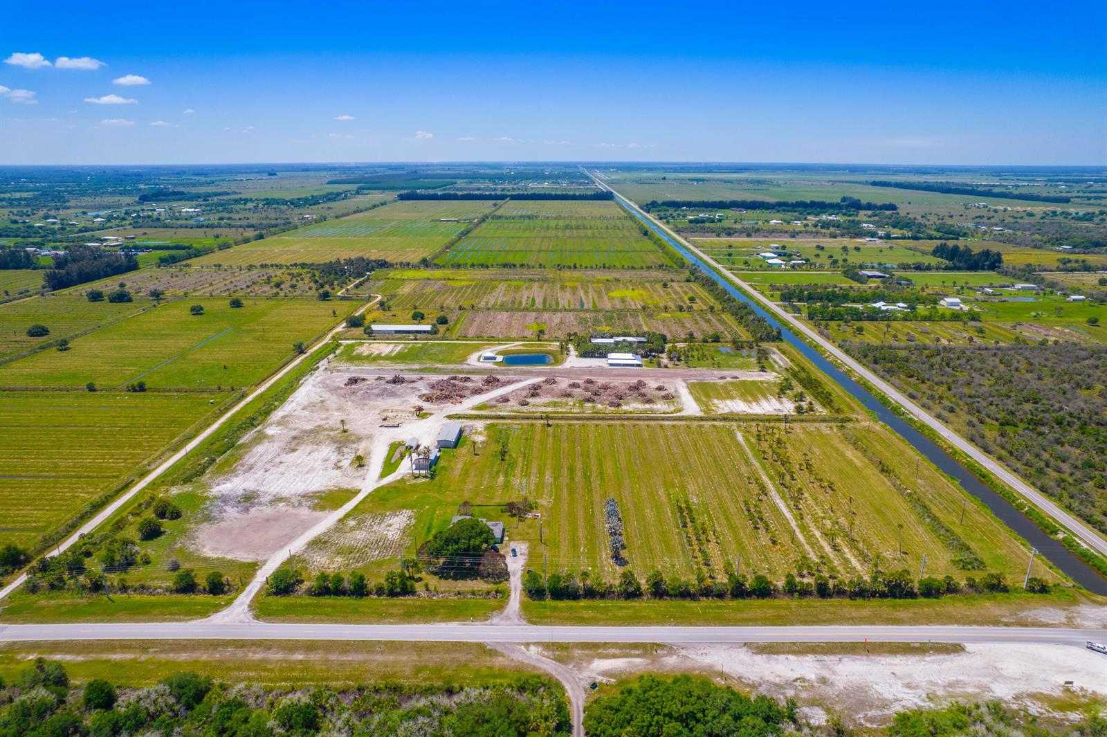 An aerial view shows a large, flat rural property with agricultural fields, structures, and a canal — 0 Orange Avenue, Fort Pierce FL 34945, FORT PIERCE, FL