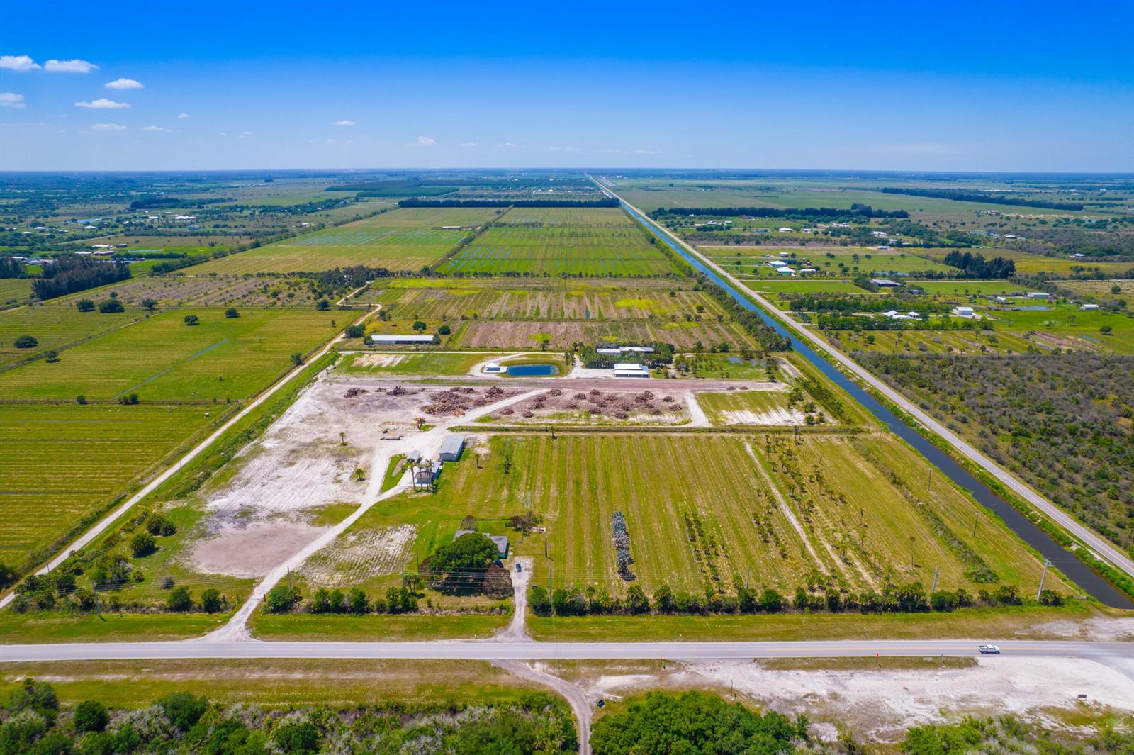 An aerial view shows a large, flat rural property with agricultural fields, structures, and a canal — 0 Orange Avenue, Fort Pierce FL 34945, FORT PIERCE, FL