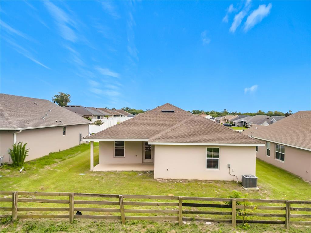 The rear exterior of a single-story house features a covered patio and a wooden fence — 187 NW 45TH LOOP, OCALA, FL