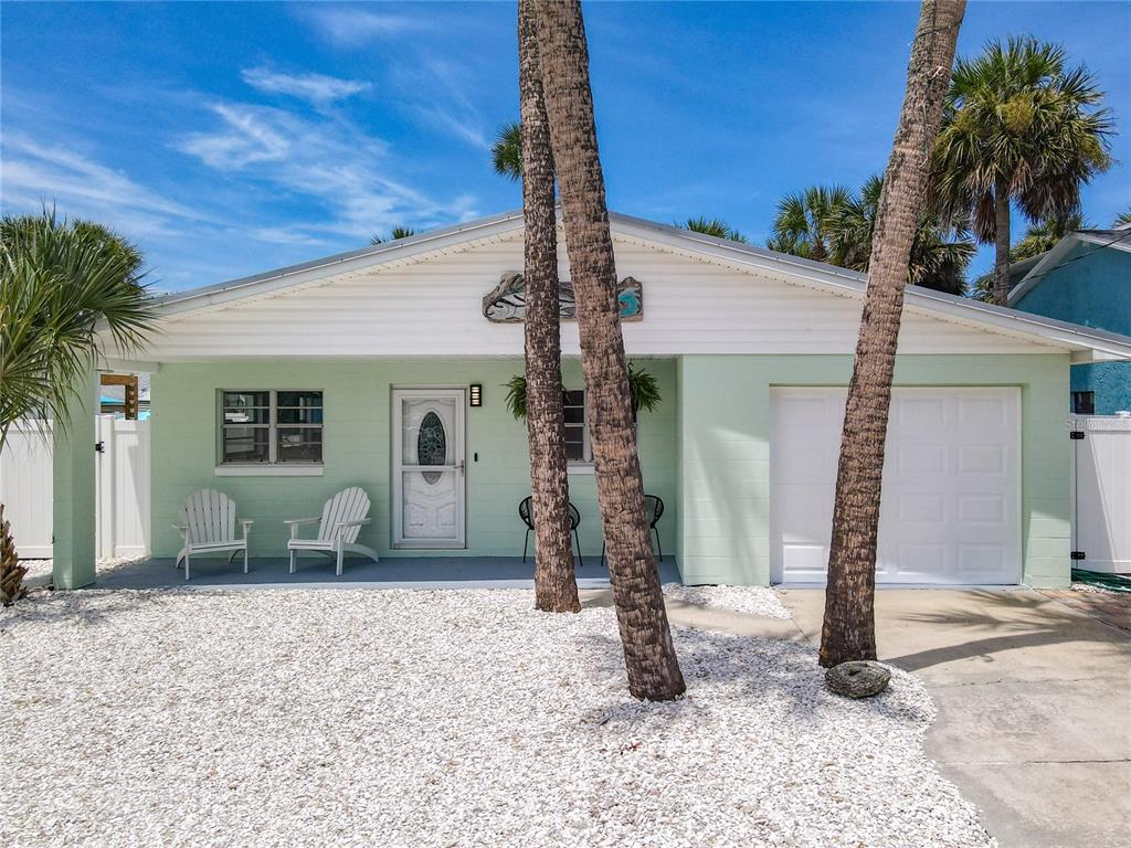 A light green single-story house with a white garage door and two palm trees — 220 CRAWFORD ROAD, NEW SMYRNA BEACH, FL