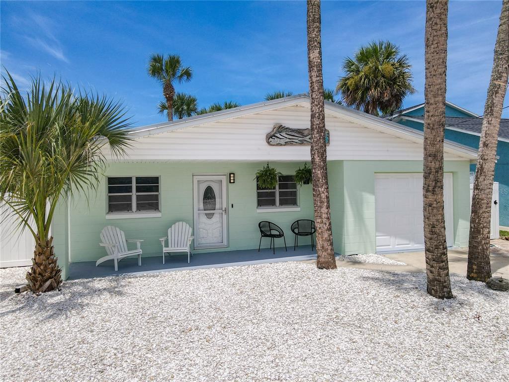 A light green single-story house with a white garage door and white gravel front yard — 220 CRAWFORD ROAD, NEW SMYRNA BEACH, FL