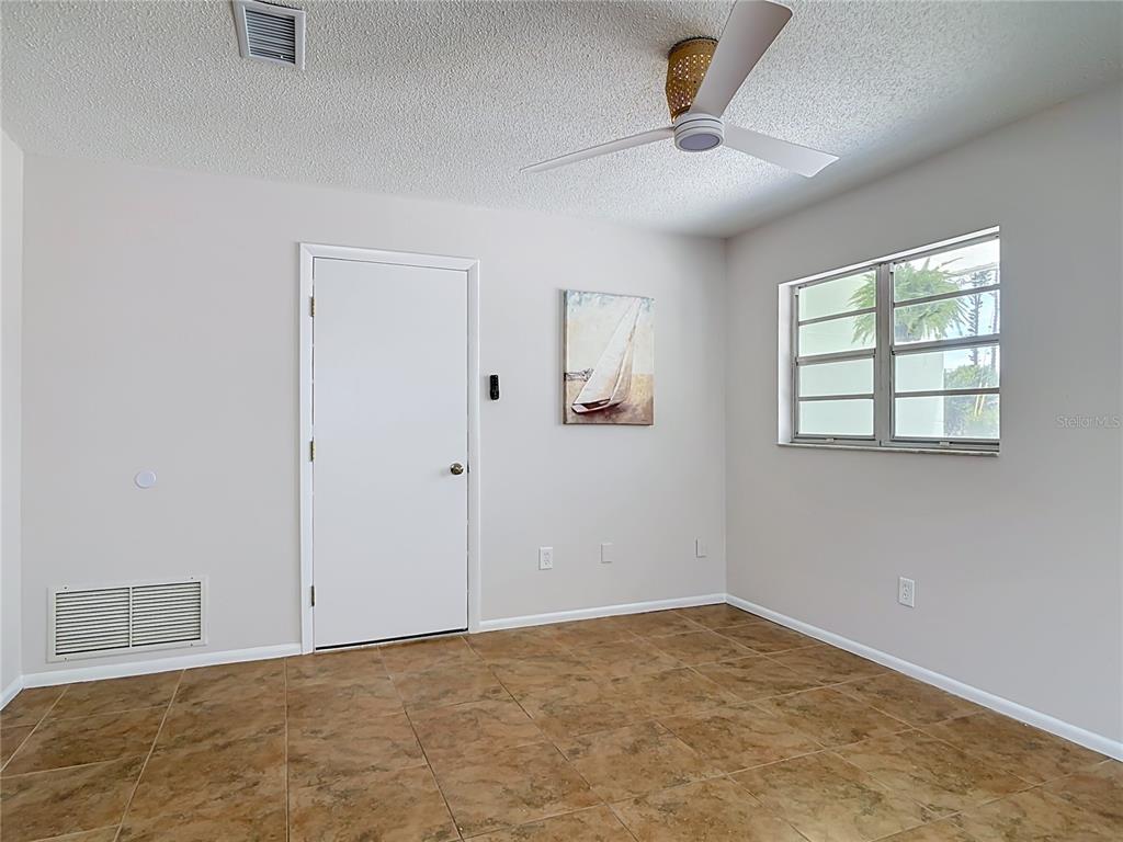 A bedroom with light walls, tile flooring, a ceiling fan, and a single window — 220 CRAWFORD ROAD, NEW SMYRNA BEACH, FL