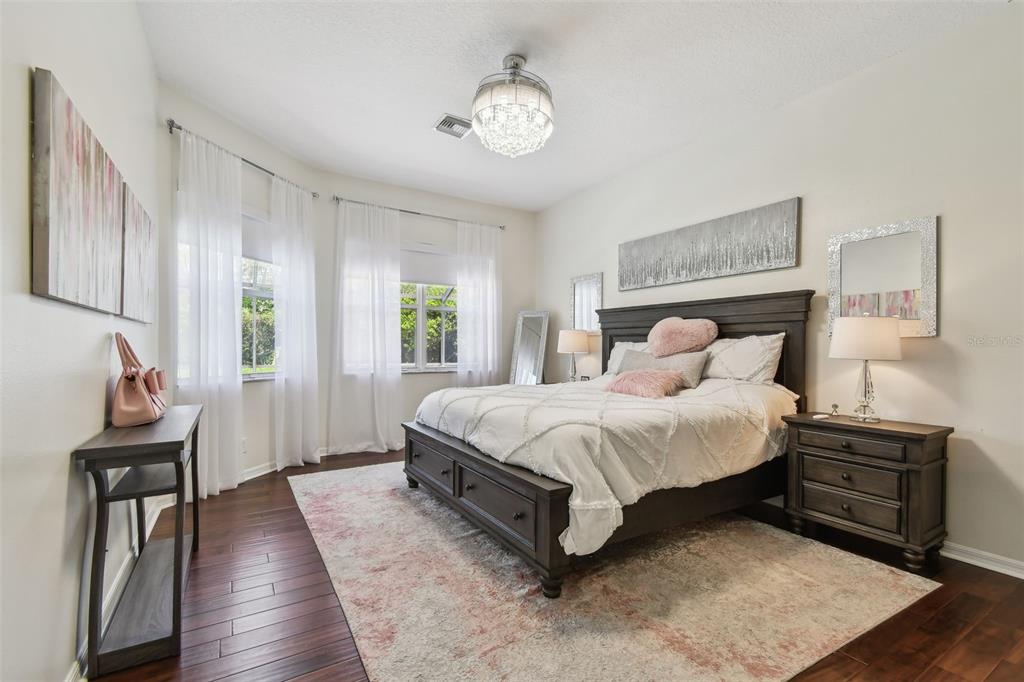 A bedroom features a dark wood bed frame, white bedding, and a light-colored area rug — 3025 NAUGHTON WAY, TARPON SPRINGS, FL