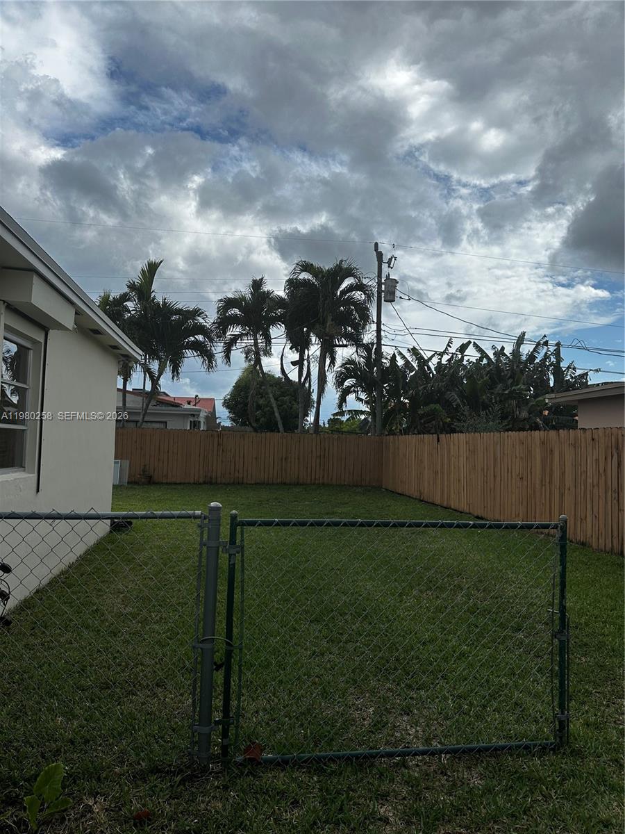 A fenced backyard features a grassy lawn, palm trees, and a wooden privacy fence — 7540 SW 37th St, Miami FL 33155, MIAMI, FL
