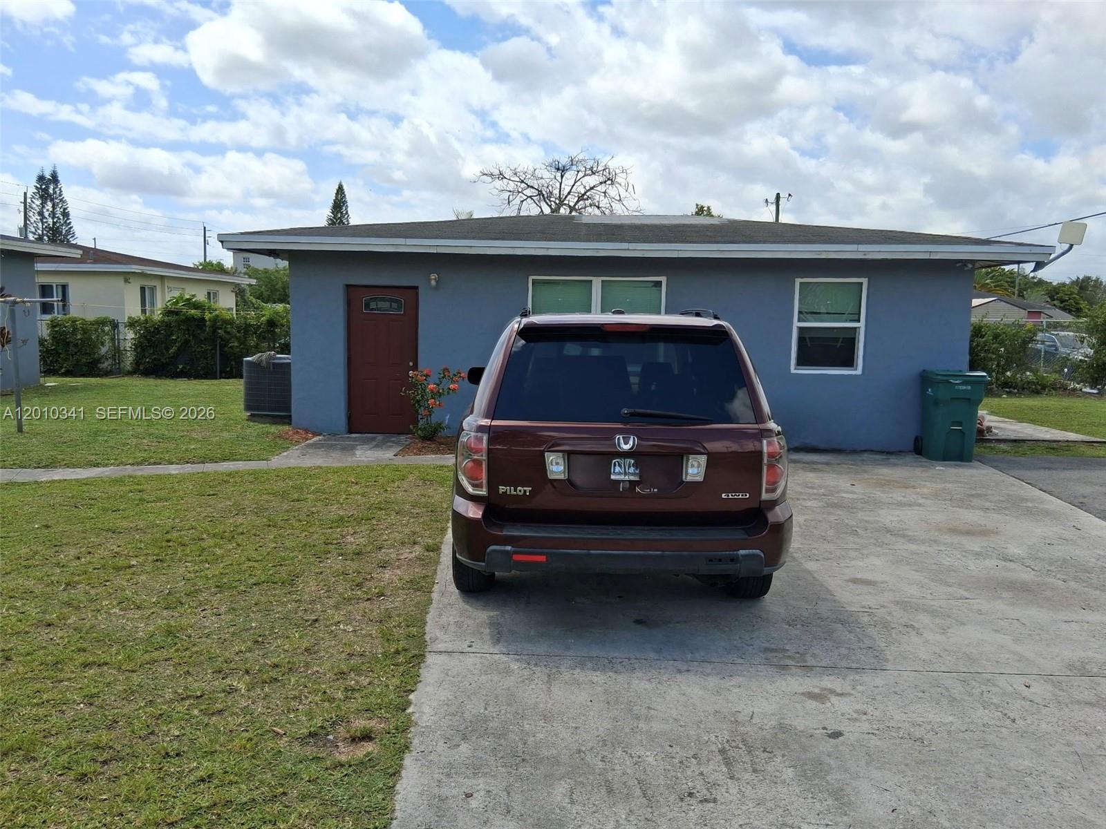 A white, single-story house with a flat roof sits on a large, grassy corner lot — 1334 NW 6th Ave, Florida City FL 33034, FLORIDA CITY, FL