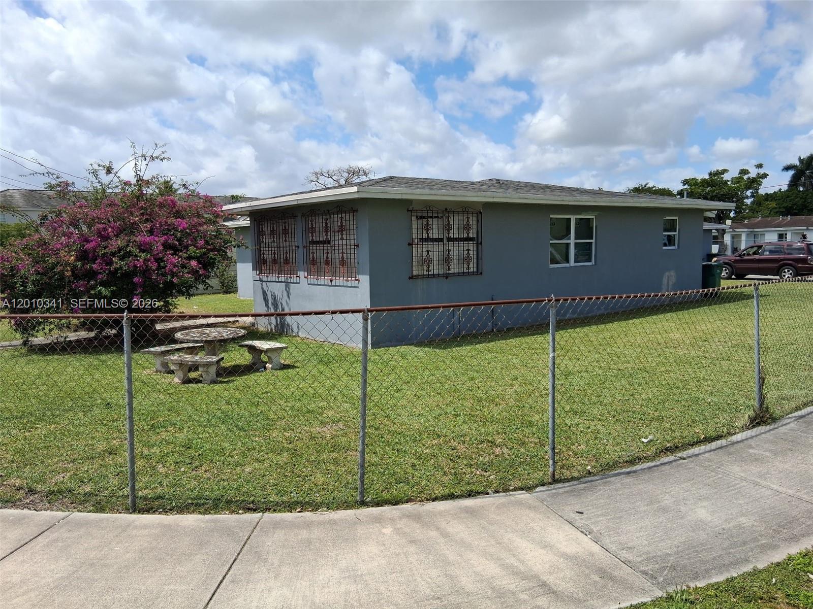 A white single-story house with security bars on the windows sits on a grassy lot — 1334 NW 6th Ave, Florida City FL 33034, FLORIDA CITY, FL