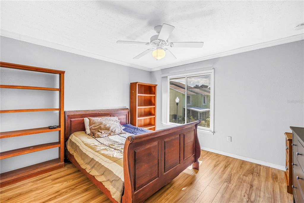 A bedroom with wood-look flooring, a wooden bed frame, two bookshelves, and a ceiling fan — 3580 41ST LANE S UNIT I, ST PETERSBURG, FL
