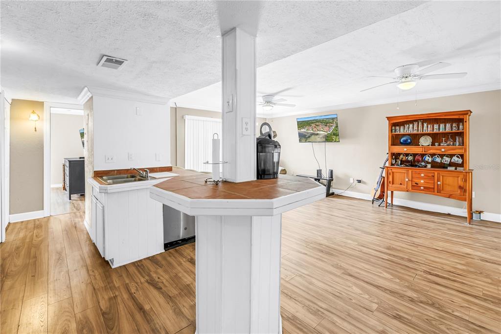 A kitchen island with a tiled countertop stands in a room with wood-look flooring — 3580 41ST LANE S UNIT I, ST PETERSBURG, FL