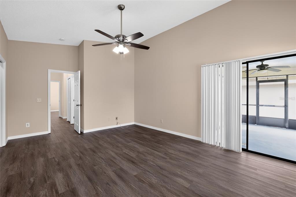 An empty room with dark wood-look flooring, a ceiling fan, and sliding glass patio doors — 5024 CYPRESS TRACE DRIVE, TAMPA, FL