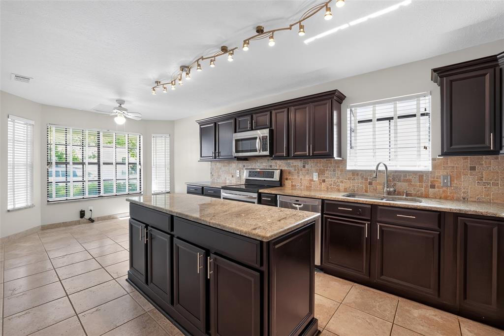 A kitchen with dark wood cabinets, granite countertops, a center island, and tile flooring — 5024 CYPRESS TRACE DRIVE, TAMPA, FL
